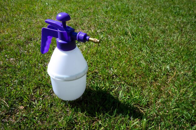 Plastic spray gun for the garden on the green grass a bottle of pest control