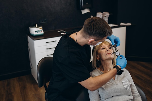 Photo a plastic surgeon examines old eye wrinkles in an elderly woman clinic of modern plastic surgery