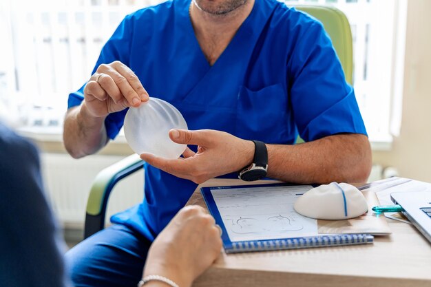 The plastic surgeon shows the patient samples of the breast implant for future surgery. A professional and experienced surgeon works in the clinic.