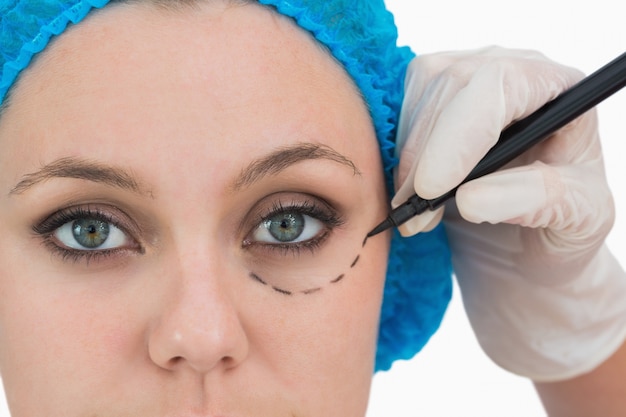 Plastic surgeon writing on the serious woman&#039;s face 