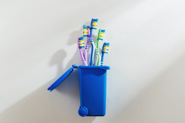 Plastic toothbrushes in trash bin on white background. Concept of Recycling plastic.