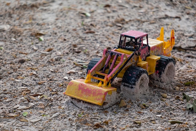 Plastic toy car damaged and abandoned in sand