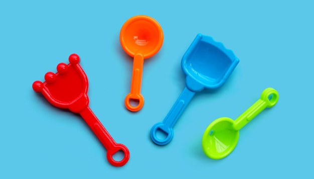 Plastic toys, shovels for sand on blue background.