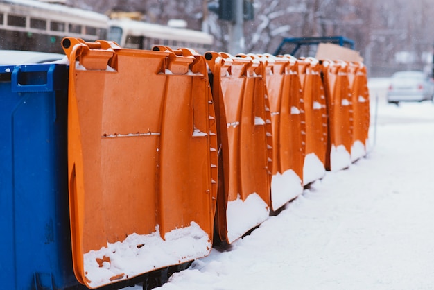 Plastic trash cans stand in a row along the road