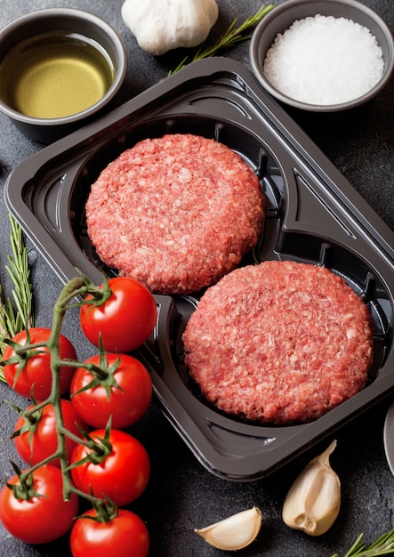 Plastic tray with raw minced homemade grill beef burgers with spices and herbs. Top view and.