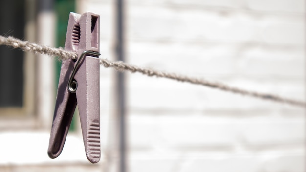 Plastic wasknijpers hangen in een rij aan het touw. Touw buitenshuis, op een onscherpe achtergrond in een zonnige tuin. Waslijn op straat. Wasknijpers.