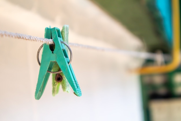 Plastic wasknijpers hangen in een rij aan het touw. Touw buitenshuis, op een onscherpe achtergrond in een zonnige tuin. Waslijn op straat. Wasknijpers.