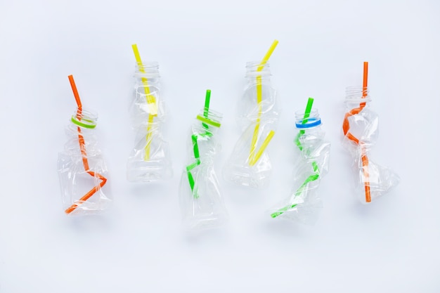 Plastic waste, Plastic bottles with straws on white background.