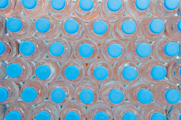 플라스틱 물병 배경 파란색 병 뚜껑 질서정연한 배열 파란색 배경의 플라스틱 병에 있는 상쾌한 천연 미네랄 워터 행에 대한 오버헤드 보기