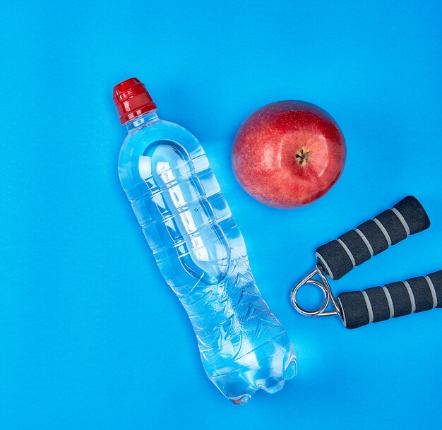 Plastic water bottle, red ripe apple and sports expander 