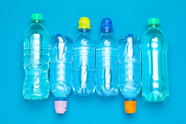 Plastic water bottles with caps of different colour on the  table