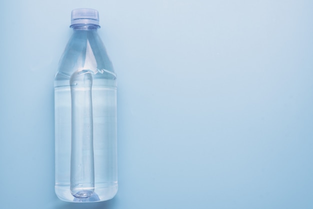 Plastic waterfles op blauwe oppervlakteachtergrond