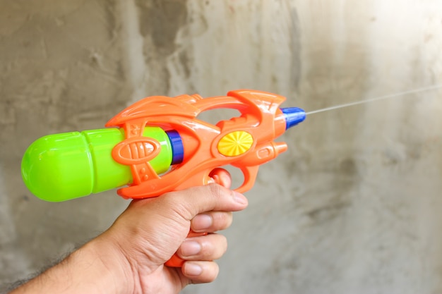 Plastic waterpistool dat op groene achtergrond wordt geïsoleerd