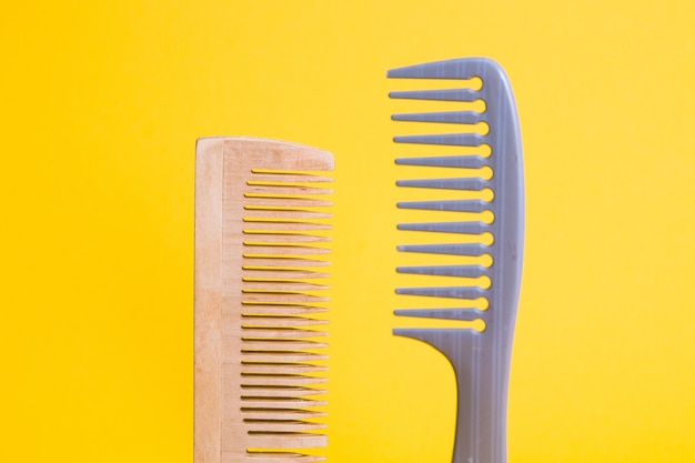Plastic and wooden combs on a yellow background