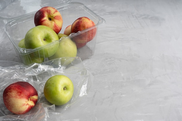 Plastic zak en container vol rijpe appels en nectarines op beton