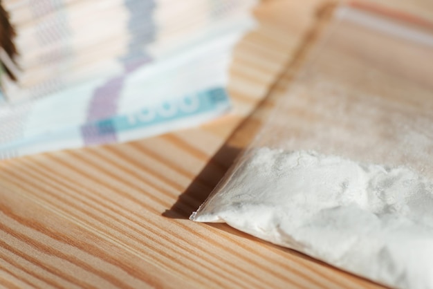 Plastic zak met drugs en stapel oekraïens hryvnia-geld op houten tafel drugshandel drugsmisbruik concept