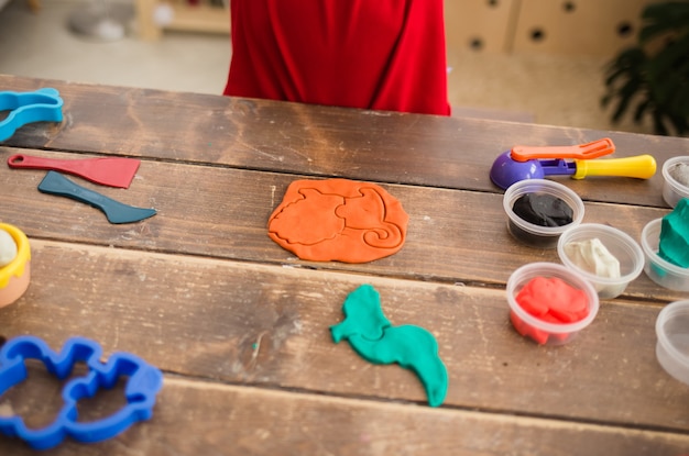 Plasticine and molds with plasticine on a wooden table with accessories for creativity