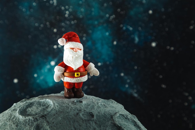 Plasticine Santa Claus on the moon against the background of the starry sky Christmas card
