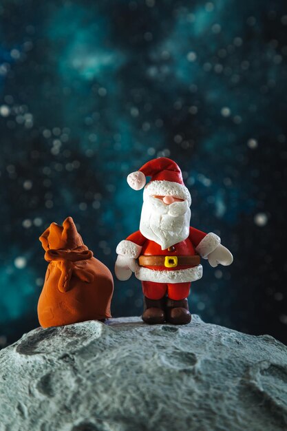 Plasticine Santa Claus with a bag of gifts on the moon Christmas card