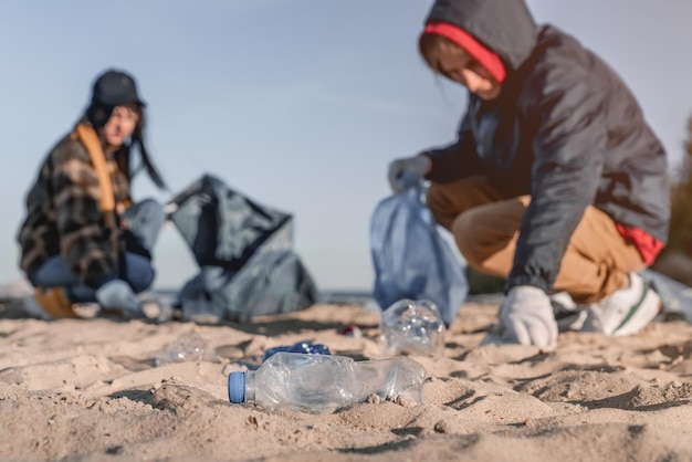 Plastics op het strand met een groep vrijwilligers op de achtergrond Focus op plastic op de voorgrond