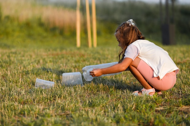 Plasticvervuiling in het milieuprobleem van de wereld een hand in een blauwe handschoen stopt afval in een plastic zak verwijdering en reiniging van afval uit besmette gebieden