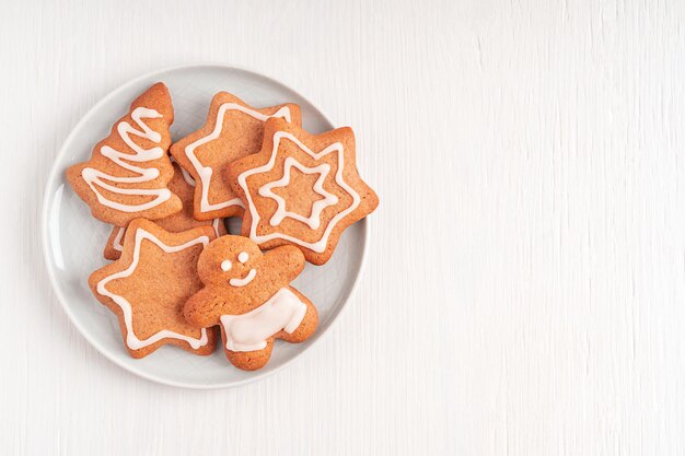 Plat gelegd met bord zelfgemaakte zoete peperkoekkoekjes met suikersuikerglazuur geserveerd op houten tafel