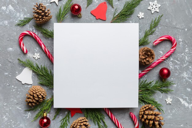 Plat lag kerstcompositie vierkant papier blanco pijnboomtakken kerstversiering op gekleurde achtergrond bovenaanzicht kopieerruimte voor tekst