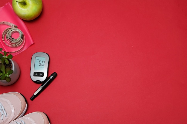 Plat lag met dieet diabetes gewichtsverlies concept. Sneakers, meetlint, glucometer op een rood