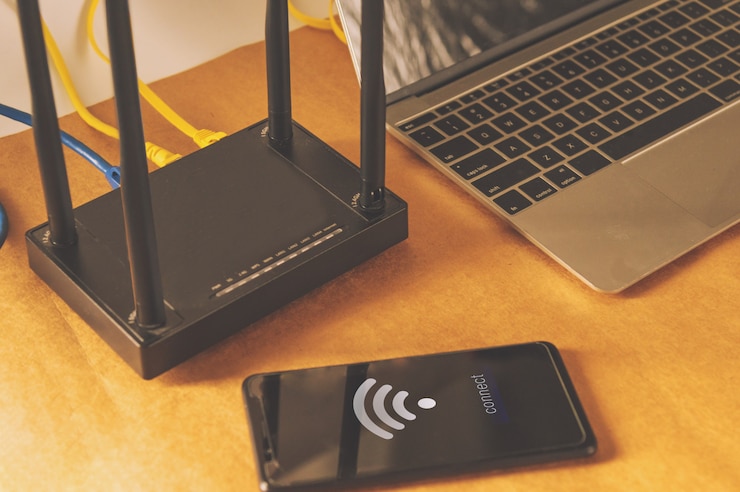Foto plat lag office-tafel met wifi-router, computer en benodigdheden bovenaanzicht