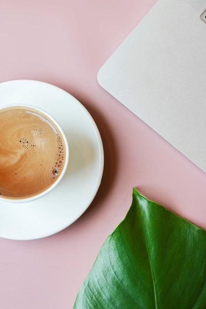 Plat lag samenstelling met koffie, laptop en monstera op roze