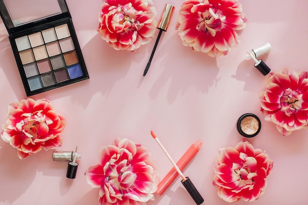 Plat lag samenstelling met producten voor decoratieve make-up op een roze tafel. Schoonheidstafel