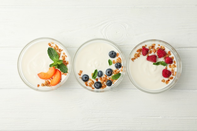 Plat lag samenstelling met yoghurt desserts en ingrediënten op witte houten achtergrond