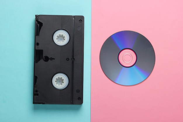 Plat lag samenstelling van cd-schijf, audiocassette op roze blauw. Retro opslagmedia.