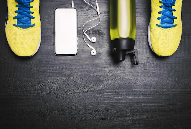 Plat lag shot van sportuitrusting Sneakers water oortelefoons en telefoon op houten achtergrond