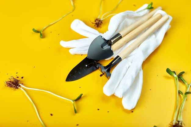 Foto plat lag tuingereedschap handschoenen en greens op gele achtergrond