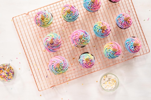Plat leggen. Chocolade eenhoorn cupcakes versieren met kleurrijke buttercream icing en hagelslag.