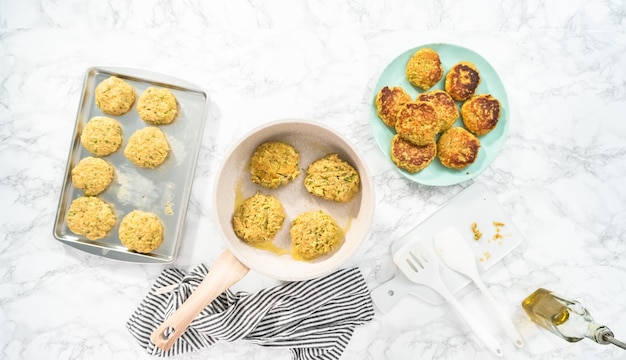 Plat leggen. Courgettekoekjes bakken in olijfolie op een koekenpan.