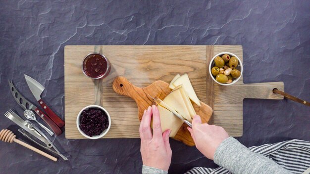 Plat leggen. Gastronomische kaas, crackers en fruit op een bord schikken voor een grote kaasplank.