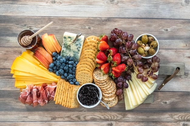 Plat leggen. Gastronomische kaas, crackers en fruit op een houten snijplank dienden als aperitief.