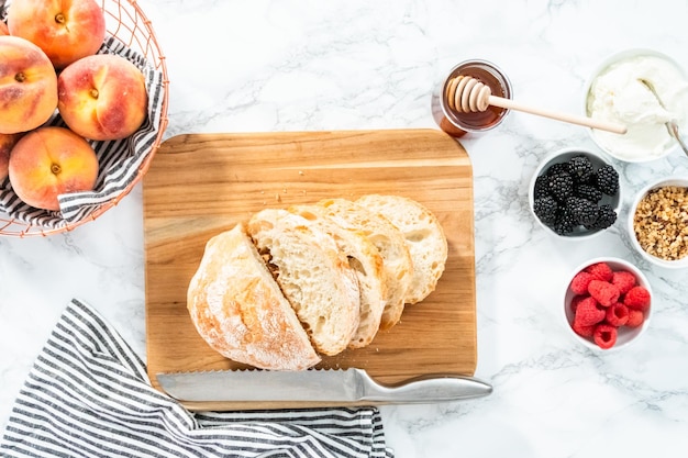 Plat leggen. Ingrediënten voor het bereiden van perzik ricotta toast op een marmeren aanrecht.