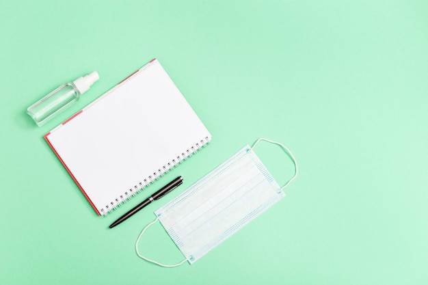 Plat leggen met persoonlijke beschermingsmiddelen Gezicht medisch masker handdesinfecterend notebook pen