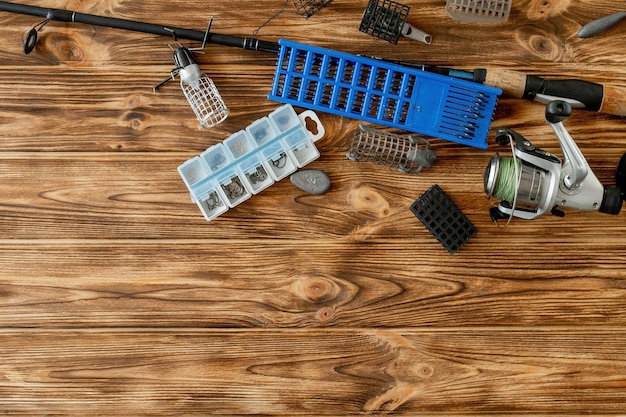 Plat leggen met visgerei hengel en plastic doos met visgerei en haken feeders op houten planken kopiëren ruimte