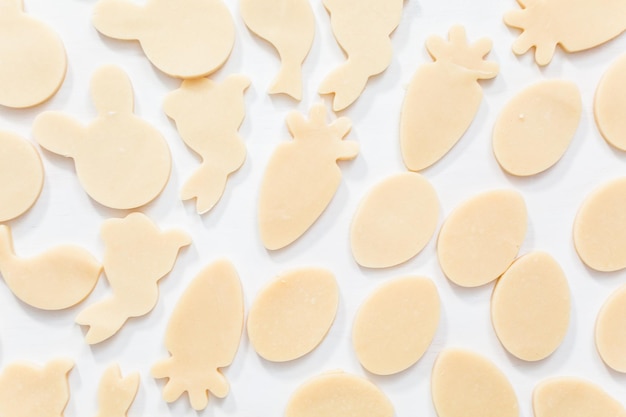 Plat leggen. Ongebakken Pasen-suikerkoekjes op een witte tafel.