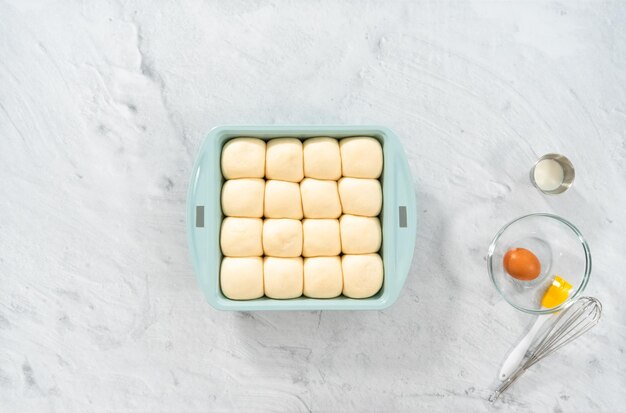 Plat leggen. Rijzende dinerbroodjes in de bakvorm.