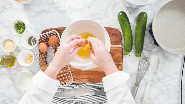 Plat leggen. Stap voor stap. Biologische bruine eieren breken in de kom om courgettecakes te maken.