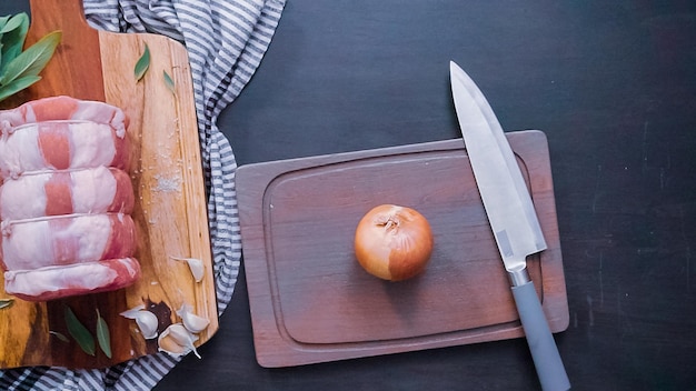 Plat leggen. Stap voor stap. Gele ui in blokjes snijden op een houten snijplank.