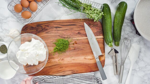 Plat leggen. Stap voor stap. Het mengen van verse kruiden en zure room om kruidenzure room te maken.