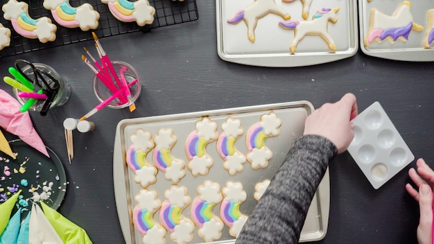 Plat leggen. Stap voor stap. Het schilderen van voedselglitter op eenhoornsuikerkoekjes met royal icing.