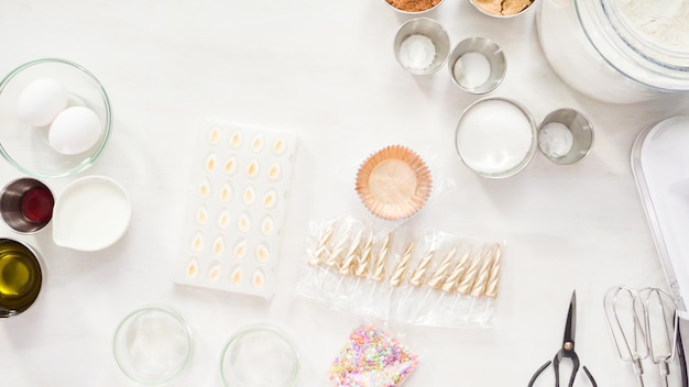 Plat leggen. Stap voor stap. Ingrediënten op de witte tafel om cupcakes met eenhoornchocolade te maken.