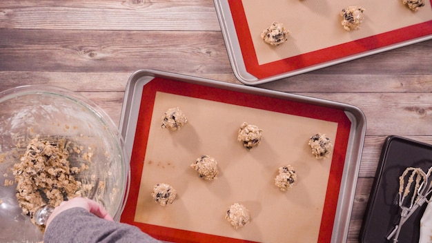 Plat leggen. Stap voor stap. Koekjesdeeg met een deeglepel in de bakplaat scheppen.